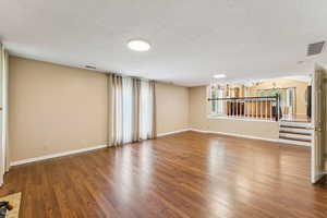 Unfurnished living room with a chandelier, a textured ceiling, and wood finished floors