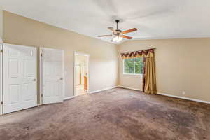 Unfurnished bedroom with vaulted ceiling, carpet floors, ceiling fan, and ensuite bath