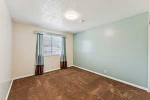 Spare room featuring carpet floors, a smoke detector, and a textured ceiling