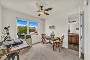 Home office featuring light carpet and a ceiling fan