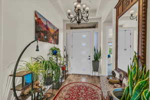 Foyer with a chandelier, wood finished floors, and a tray ceiling