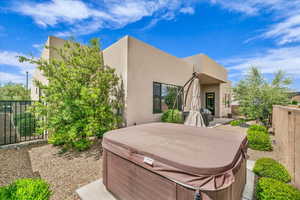 Rear view of house featuring a hot tub and stucco siding