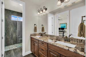 Bathroom featuring a shower stall, double vanity, and ceiling fan