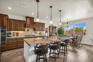 Kitchen with premium range hood, stainless steel appliances, decorative backsplash, recessed lighting, and wood finished floors