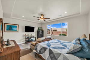 Bedroom featuring a tray ceiling, recessed lighting, a ceiling fan, and wood finished floors