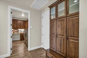 Hall with separate washer and dryer and dark wood-style flooring