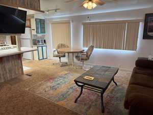 Carpeted living area featuring ceiling fan and rail lighting