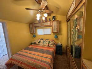 Carpeted bedroom with lofted ceiling and a ceiling fan