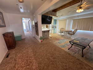 Carpeted living room featuring ceiling fan and baseboards