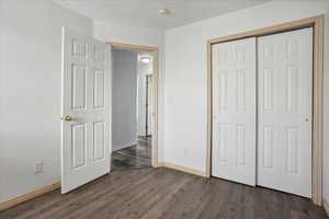 Unfurnished bedroom featuring dark wood-type flooring and a closet