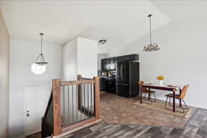 Kitchen with freestanding refrigerator, gas stove, a chandelier, dark wood finished floors, and hanging light fixtures