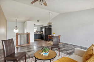 Living room with vaulted ceiling, a ceiling fan, and dark wood-style flooring