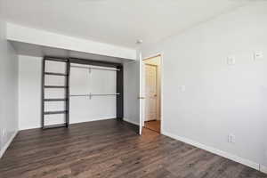 Unfurnished bedroom with dark wood-style floors and a closet
