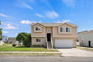 Bi-level home with stucco siding, a garage, and concrete driveway
