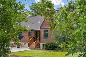 View of front of house featuring brick siding, a front lawn, a patio, and a shingled roof