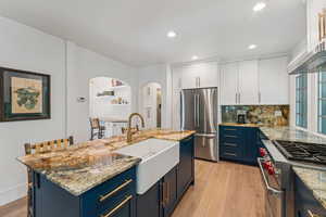 Kitchen with appliances with stainless steel finishes, blue cabinets, white cabinetry, tasteful backsplash, and recessed lighting