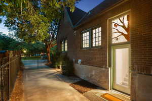 View of side of property featuring brick siding, a gate, and a shingled roof