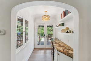 Doorway to outside with french doors, hardwood / wood-style flooring, a chandelier, and arched walkways