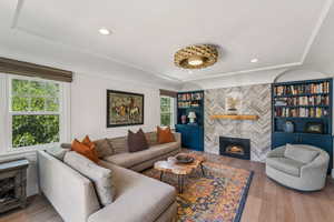 Living room with healthy amount of natural light, a tiled fireplace, wood finished floors, and recessed lighting