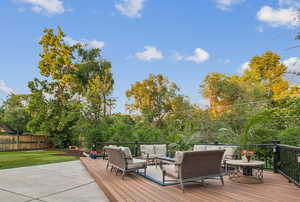 Wooden terrace with an outdoor hangout area and a fenced backyard