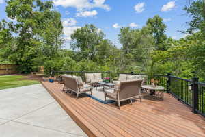 Wooden terrace with an outdoor hangout area and view of wooded area