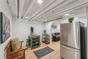 Kitchen featuring freestanding refrigerator, arched walkways, light wood finished floors, and open shelves
