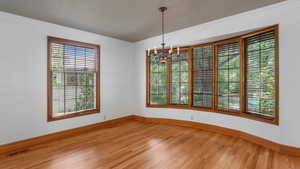 Empty room featuring a chandelier, light wood-type flooring, and crown molding