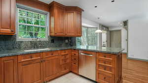 Kitchen featuring stainless steel dishwasher, brown cabinetry, a peninsula, tasteful backsplash, and recessed lighting