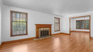 Unfurnished living room with wood finished floors, crown molding, and a fireplace