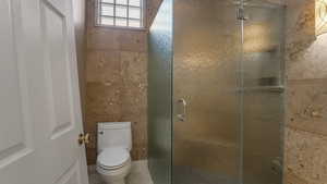 Bathroom featuring tile walls and a shower stall