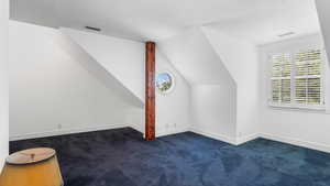 Bonus room featuring dark carpet and lofted ceiling