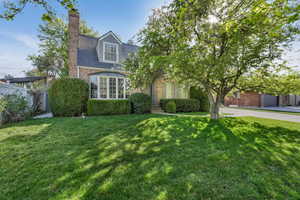 View of front of house featuring brick siding, a front lawn, and a chimney