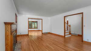 Unfurnished living room featuring a fireplace, crown molding, light wood-style flooring, and stairs