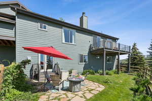 Back of property featuring a balcony, an outdoor fire pit, a chimney, and a patio area
