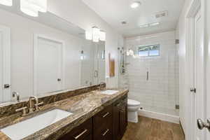 Bathroom featuring wood finished floors, a stall shower, and double vanity
