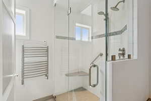 Bathroom with radiator, a stall shower, and a towel warmer