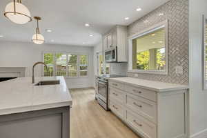 Kitchen with appliances with stainless steel finishes, recessed lighting, decorative backsplash, pendant lighting, and light wood-style floors