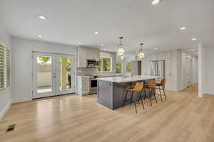 Kitchen featuring stainless steel appliances, light countertops, recessed lighting, a breakfast bar, and light wood-style flooring