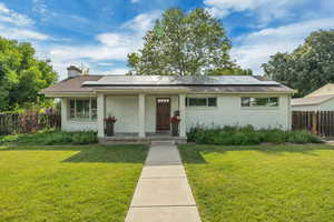 View of front of home featuring a porch, solar panels, a chimney, and brick siding