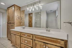 Full bathroom featuring tile patterned flooring, double vanity, and a shower stall
