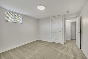Unfurnished bedroom with light colored carpet and baseboards
