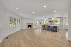 Kitchen with stainless steel microwave, a breakfast bar, recessed lighting, light countertops, and a kitchen island with sink
