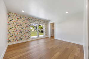 Spare room with wallpapered walls, light wood-style flooring, and recessed lighting