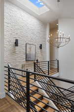 Stairs with a skylight, wood finished floors, and a chandelier