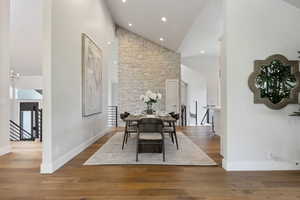 Dining space with high vaulted ceiling, wood finished floors, a chandelier, and recessed lighting