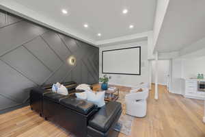 Cinema featuring light wood-style floors, a decorative wall, and recessed lighting