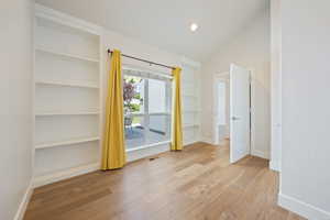 Unfurnished bedroom featuring hardwood / wood-style floors and vaulted ceiling