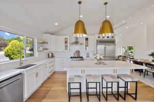 Kitchen with appliances with stainless steel finishes, a breakfast bar area, light countertops, a kitchen island, and pendant lighting