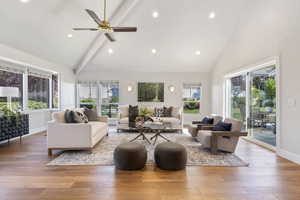 Living room featuring high vaulted ceiling, beam ceiling, plenty of natural light, wood-type flooring, and recessed lighting