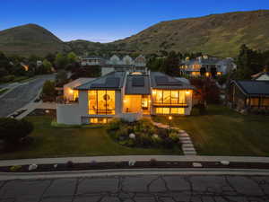 View of front of house featuring a standing seam roof, roof mounted solar panels, a balcony, a front yard, and a mountain view